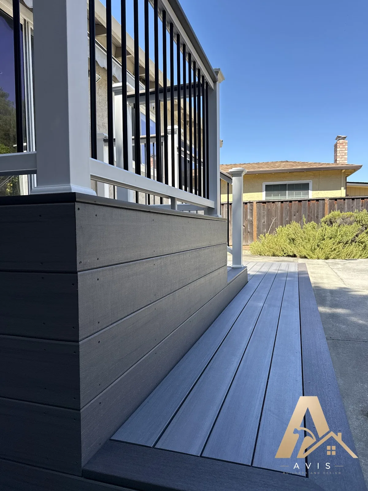 Gray composite deck with white posts and black balusters looking out over a fenced yard